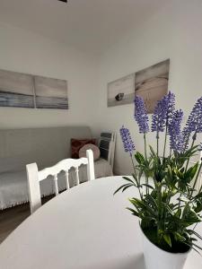un tavolo bianco con un vaso con fiori viola di La Casita de Ana a Tarifa