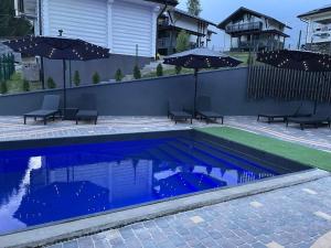 a swimming pool with chairs and umbrellas in a yard at Horizon Apartmens in Yablunytsya