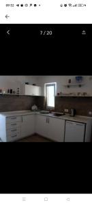 a kitchen with white cabinets and a window at Odessa Mama in Bijela