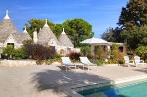a group of chairs and an umbrella next to a pool at Trullo Bosco Libero Ostuni in Ostuni