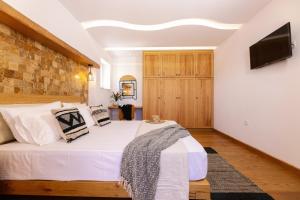 a bedroom with a white bed and a tv on a wall at Velonis Villa with private pool and sea view in Agia Anna Naxos