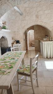 a table and chairs in a kitchen with a stone wall at Trullo Bosco Libero Ostuni in Ostuni