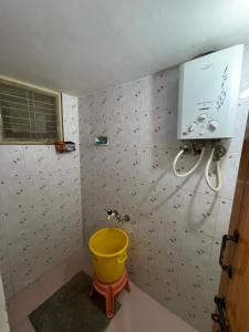 ein Badezimmer mit einem gelben Eimer in einem Zimmer in der Unterkunft Sahithya Sadana in Sringeri
