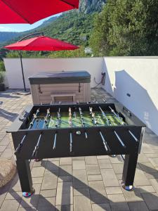 a ping pong table sitting on a patio with an umbrella at Apartman Koko with private jacuzzi in Makarska