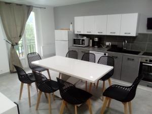 a kitchen with a white table and chairs at appt tout confort a laveissiere 103 in Laveissière +10 photos