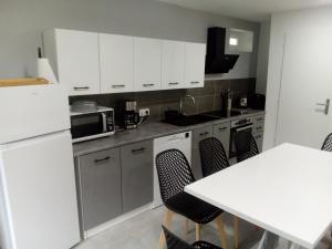 a kitchen with white cabinets and a white table and chairs at appt tout confort a laveissiere 103 in Laveissière