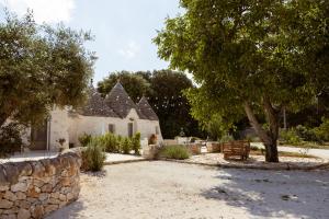 a house with a stone wall and a tree at Il Trullo di Pozzallegro in Locorotondo