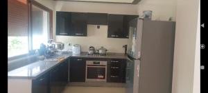 a kitchen with black cabinets and a white refrigerator at Ilyass Garden Beach Sidi Rahal in Dar Hamida
