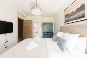 Un dormitorio con una cama blanca y un televisor de pantalla plana. en SUNNY MEGEVE - Luxury Flat with services, en Megève