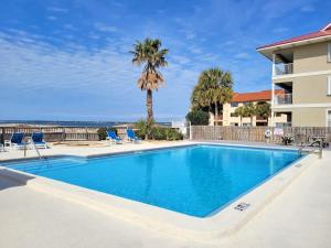 a pool with chairs and a palm tree and a building at Sunset Harbor The Palms in Navarre