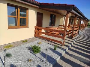 une rangée de bancs sur la terrasse couverte d'une maison dans l'établissement Bursztynowe Zacisze Domek 2 Chłopy ul Turystyczna 6, à Chłopy
