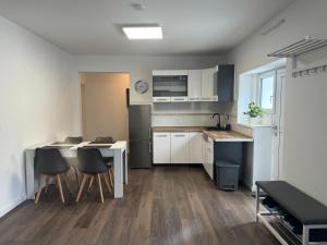 DierdorfにあるNeue Ferienwohnung Dierdorfの白いキャビネットとテーブルと椅子のあるキッチン