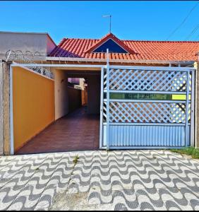 a gate to a house with a building with a red roof at Casa KAIS Peruíbe in Peruíbe