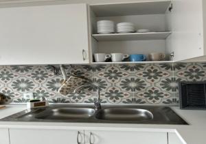 una cucina con lavandino e parete piastrellata di Casa Ana a Nazaré Altre 72 foto