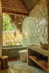 a bathroom with a tub and a stone wall at Cabin Nestled in Bamboo Forest in Armenia