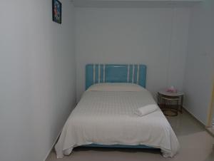 a small bedroom with a bed with a blue headboard at Guest House in Jodoh