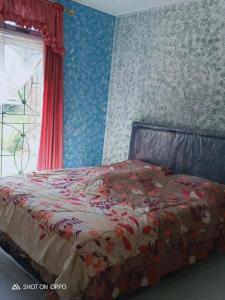a bedroom with a large bed with a red comforter at Vila bukit cipendawa in Pacet