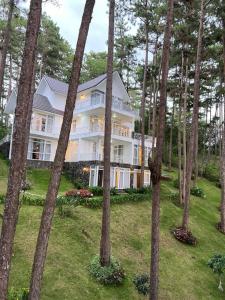 ein großes weißes Haus umgeben von Bäumen in der Unterkunft Villa Hồ Tuyền Lâm Đà Lạt View Rừng Thông Đà Lạt in Xuan An + 15 Fotos