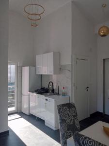 a kitchen with white cabinets and a table and a chair at Apartman Bećir in Budva