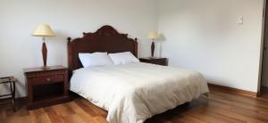 Saint-AdelmeMotel M的卧室配有一张白色床、两个床头柜和两盏灯。