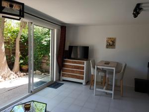 a living room with a table and a television and a table and chairs at Moon location in Cap d'Agde