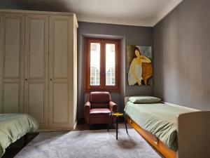 a bedroom with two beds and a chair and a window at Casa Feliciani - MonferratoHome in Viarigi