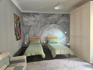 a bedroom with two beds and a mural on the wall at Casa Feliciani - MonferratoHome in Viarigi