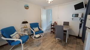 a living room with blue chairs and a table at Appartement RdC en bordure de forêt in La Barre-de-Monts