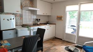 a kitchen with white cabinets and a table and a window at Appartement RdC en bordure de forêt in La Barre-de-Monts