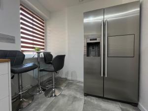 a kitchen with a stainless steel refrigerator and chairs at Apartament EROS Rynek in Bolesławiec