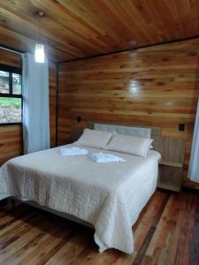a bedroom with a bed in a wooden room at Recanto do Ipê (cabana 02) in Urubici