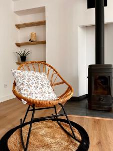 a wicker chair sitting in a living room with a stove at Maison paisible et charmante in Vendoeuvres