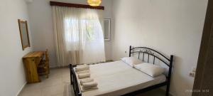 a bedroom with a bed with white sheets and a window at La casa di Voula in Néa Seléfkeia