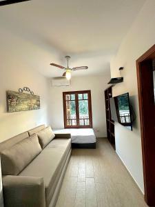 Una sala de estar con un sofá y un ventilador de techo. en Novo Duplex em condomínio com piscina Juquehy, en São Sebastião