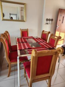 a dining room table with red chairs and a mirror at 88 on Stella Maris in Amanzimtoti