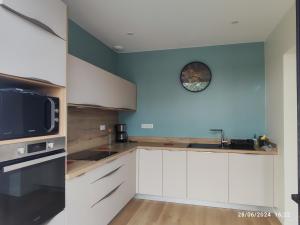 a kitchen with white cabinets and a clock on the wall at Gîte classé 4 étoiles Mulhoa in Hasparren