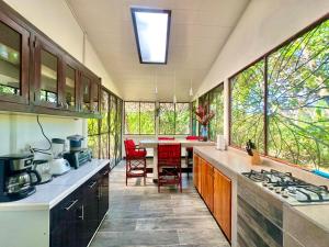 a large kitchen with a table and chairs and windows at Casa Del Bambu in Puerto Jiménez