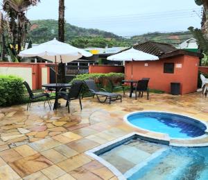 a patio with a pool and chairs and an umbrella at Novo Duplex em condomínio com piscina Juquehy in São Sebastião