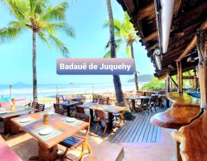 a restaurant on the beach with tables and chairs at Novo Duplex em condomínio com piscina Juquehy in São Sebastião