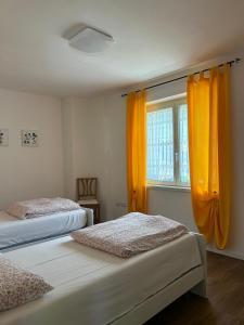 two beds in a room with orange curtains at Appartamenti Lilia - Ledro in Tiarno di Sopra