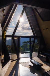 a room with a large window with the sun shining through at Chalé Com Banheira e Piscina - Urubici- SC in Urubici +2 photos