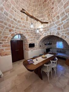Un comedor con una mesa y una pared de piedra. en Trullo Elisabetta, en Ceglie Messapica