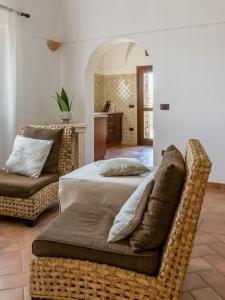 a bedroom with a bed and a rattan couch at Dammuso Meraki in Pantelleria