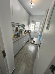a kitchen with white cabinets and a wooden floor at Apartament Nina in Bucharest