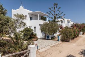 a white house with trees and bushes in front of it at Nefeli in blue in Plaka