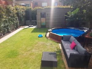 a backyard with a pool and a couch in the grass at B&B Alegría in Mechelen