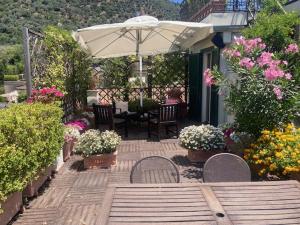 a patio with a table and an umbrella and flowers at Hepburn Holiday Home in Salerno