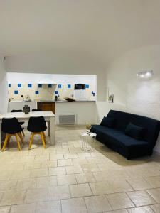 a living room with a black couch and a kitchen at Hébergement Seillans in Seillans