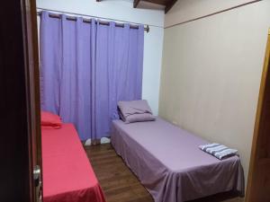 two beds in a room with purple curtains at Rincón soñado para 8 personas in Puerto Iguazú +16 photos