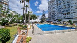 an outdoor swimming pool with palm trees and buildings at Diana Playa in Benalmádena